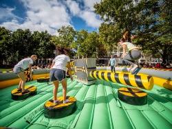 Students on a blow up jumping over a rotating arm.